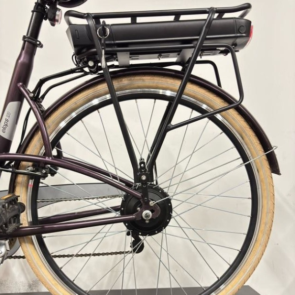 Vue arrière du vélo de ville électrique vert WAP Lille, cadrage sur la selle marron, la roue arrière, la batterie sur porte-bagages et le moteur de roue