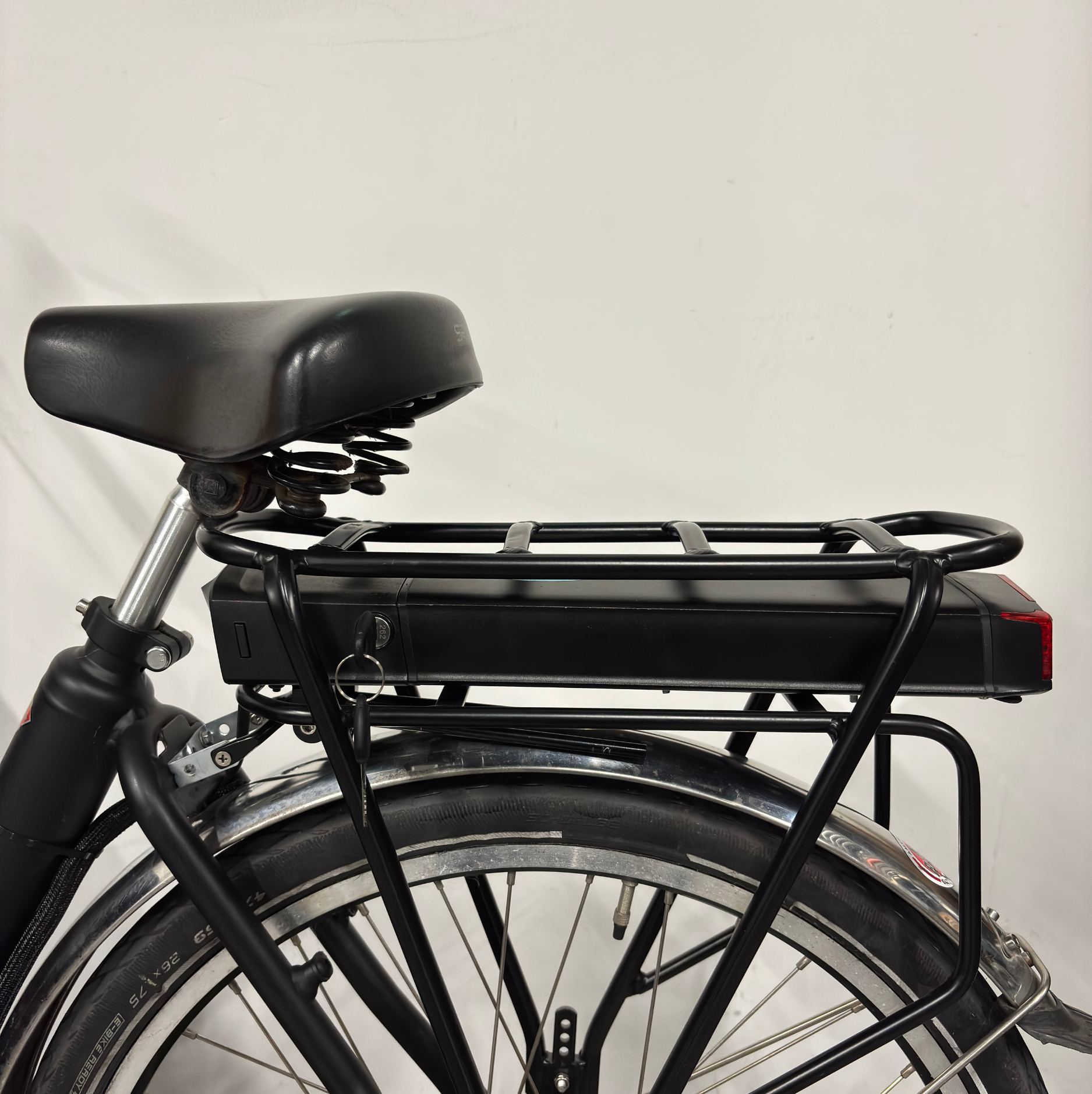 Zoom sur la partie arrière du vélo cargo électrique noir WAP Lille, avec selle noire, batterie intégrée au porte-bagages et roue arrière