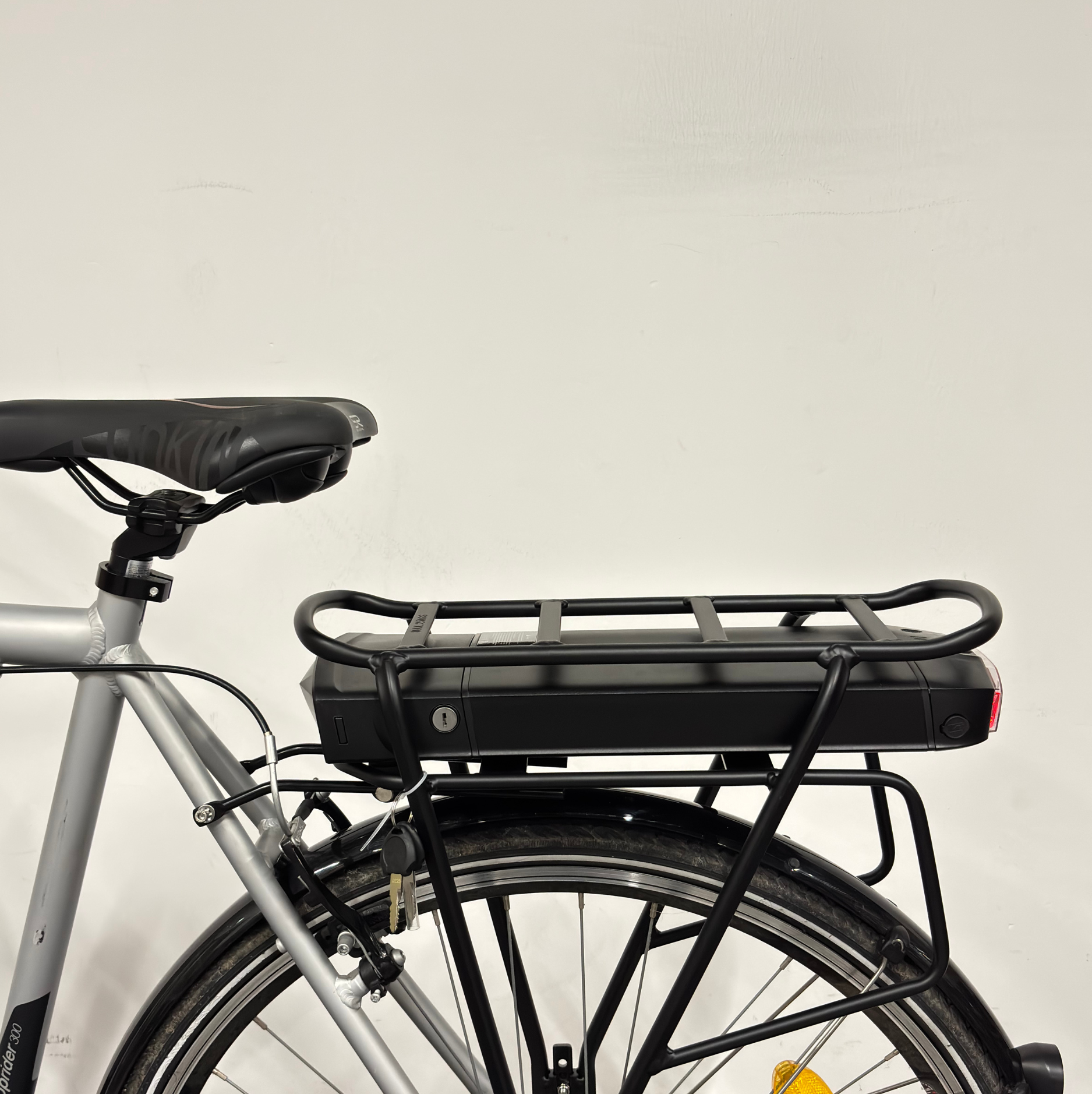 Vue arrière du vélo de ville électrique gris Btwin avec porte-bagages et batterie intégrée sur la roue arrière
