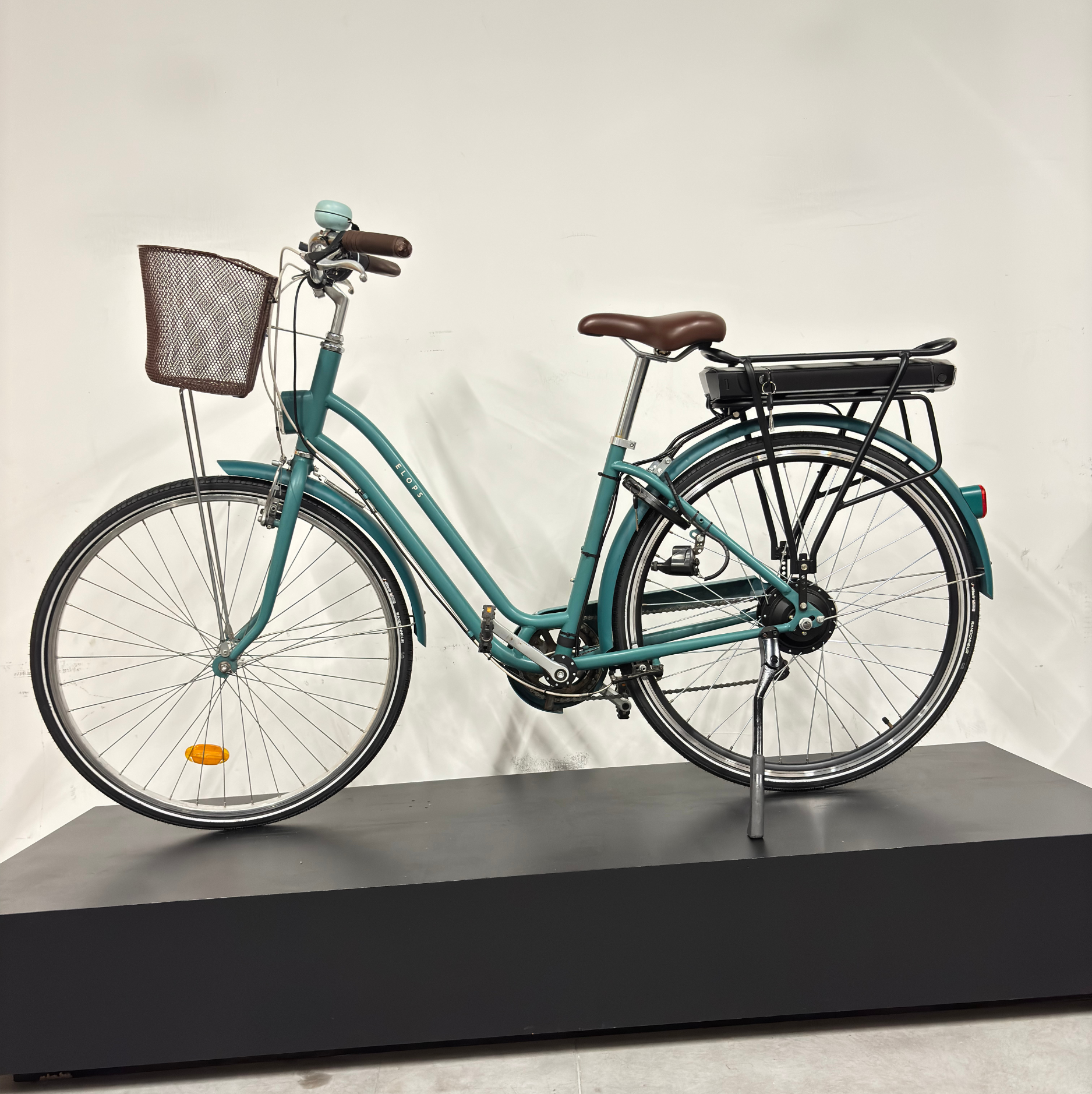 Vélo de ville électrique vert cadre bas WAP Lille, vu de profil côté droit, avec panier avant, selle marron et batterie sur porte-bagages
