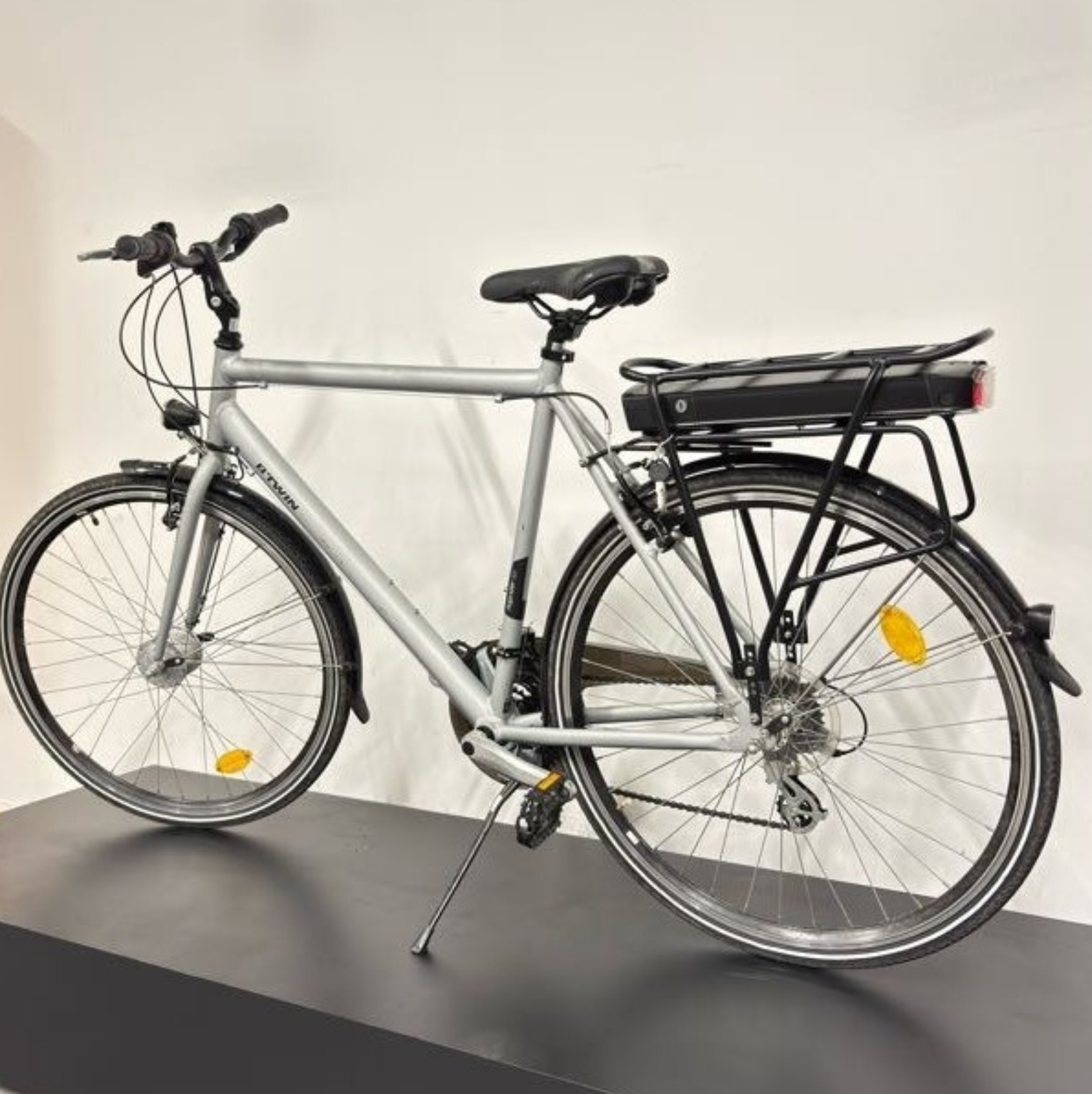 Vélo de ville électrique gris Btwin sur présentoir avec décoration de Noël et mention Offres Noël